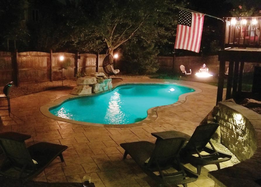 Residential pool surrounded by decking and landscaped outdoor living space