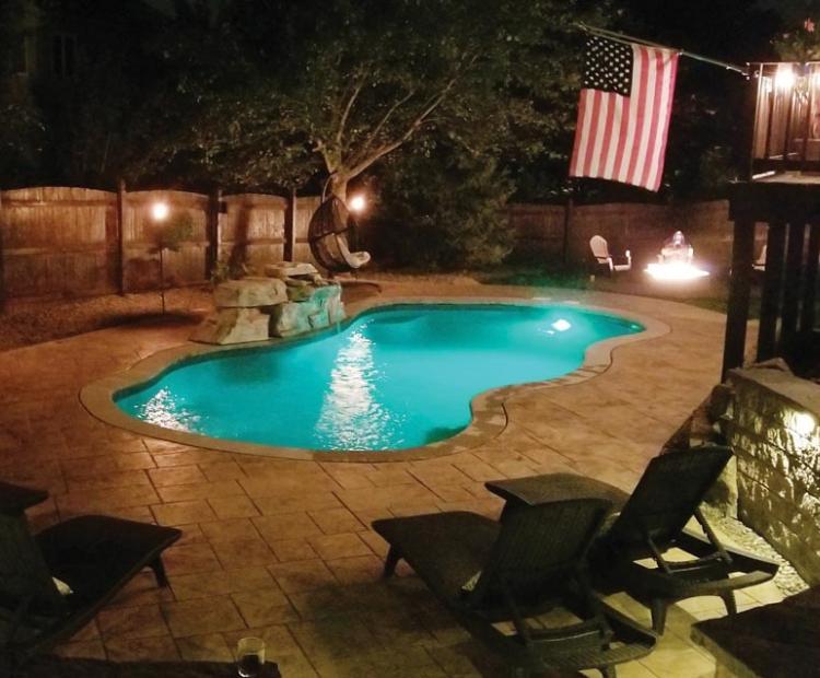 Residential pool surrounded by decking and landscaped outdoor living space